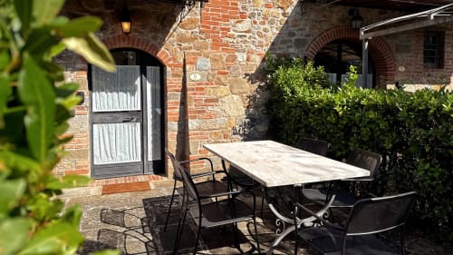 Outdoor dining patio at Borgo di Erboli, Cavriglia - stone building with table, chairs, and lush greenery