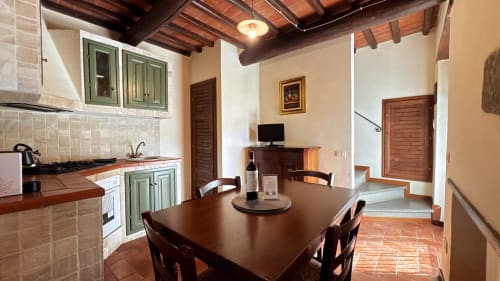 Borgo di Erboli family apartment in Cavriglia with dining table, equipped kitchen, TV, and wooden beamed ceiling