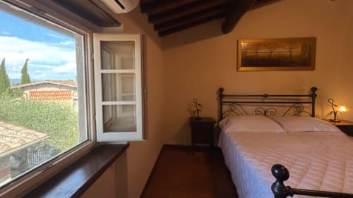 Tuscan bedroom at Borgo di Erboli with wrought iron bed, warm terracotta walls, and countryside views through large windows