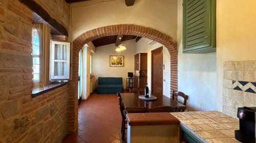 Borgo di Erboli family apartment in Cavriglia with rustic brick arch, terracotta floors, dining area and living space