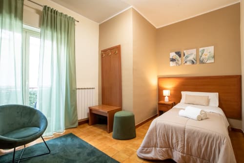 Camera singola a La Zagara Rooms a Milazzo con letto in legno, arredamenti moderni e vista sulla corte interna