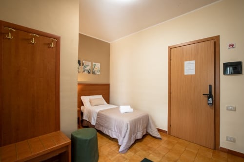Camera singola con bagno privato a La Zagara Rooms a Milazzo, con letto, porte in legno e vista sulla corte interna