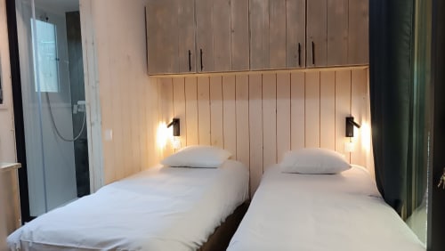 Deux lits jumeaux dans une chambre de villa moderne à l'hôtel Les Chalets Du Lac, Marange-Silvange, avec tête de lit en bois et lampes de lecture
