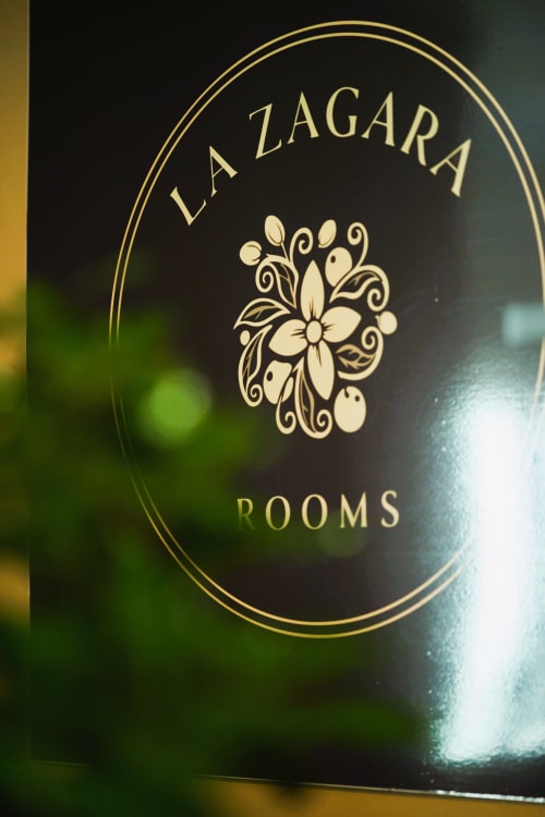 Logo elegante dorato di La Zagara Rooms con design floreale su sfondo scuro, boutique hotel a Milazzo