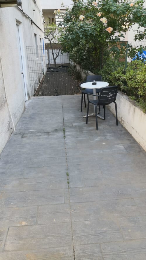 Terraza privada del Hostal Porto Mar en Salou con mesa redonda, silla negra y rosas trepadoras exuberantes bajo la luz del atardecer