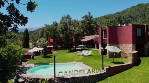 La piscina turquesa y edificios rojos de El Escondite De Pedro Malillo en el paisaje boscoso de Candeleda
