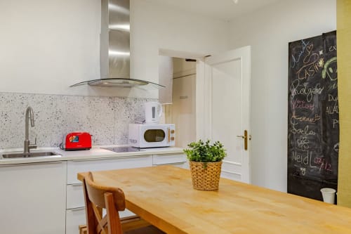 Cocina moderna en los apartamentos Tessa en Matadepera con muebles blancos, mesa de madera y pared de pizarra.