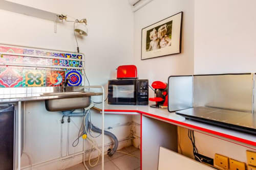 Cocina del apartamento Tessa en Matadepera con electrodomésticos rojos, azulejo decorativo colorido y fregadero de acero inoxidable