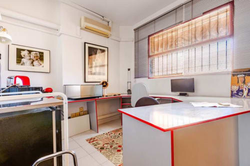 Espacio de trabajo moderno en los apartamentos Tessa en Matadepera con escritorios de ribete rojo, monitor de computadora e iluminación natural