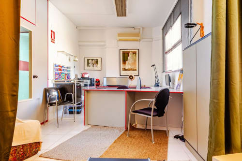 Espacio de trabajo moderno en los apartamentos Tessa en Matadepera con escritorio rojo, setup informático y mobiliario contemporáneo