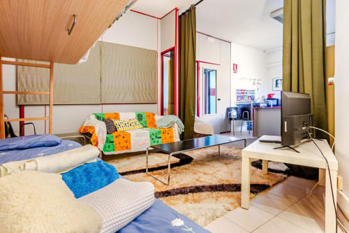 Habitación dormitorio moderno en apartamentos Tessa en Matadepera con camas coloridas, zona común compartida y diseño contemporáneo