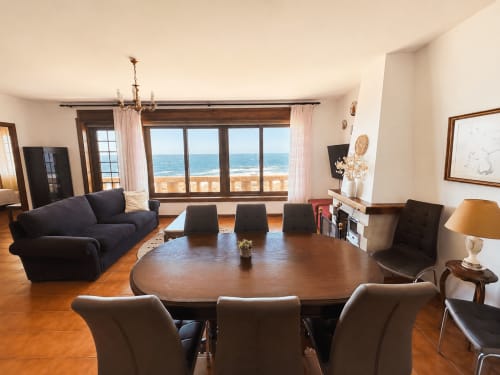 Zona de comedor y sala moderna de la villa Vila Mar de Lua en Oía con vistas al mar, mesa de madera, asientos oscuros y orientada al océano