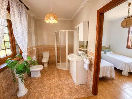 Baño espacioso en la villa Vila Mar de Lua en Oia con ducha de esquina, doble lavabo y vista al dormitorio con vistas al mar