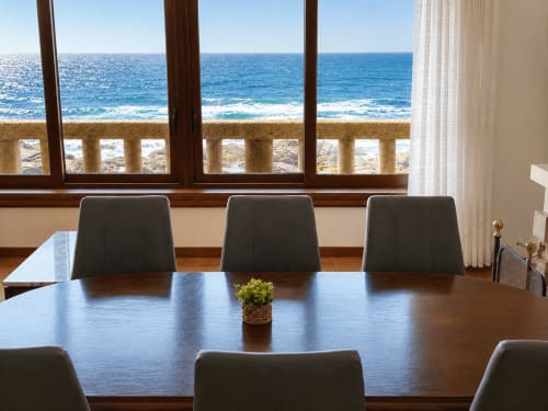 Sala de reuniones con vistas al océano en la villa Holibai en Oia, mesa de conferencia de madera y paisaje costero