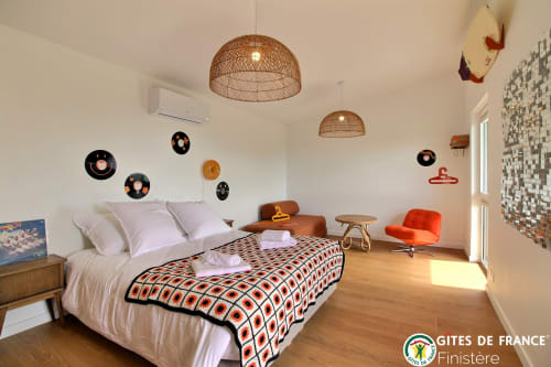 Chambre moderne de la maison d'hôtes Les écuries du bout du monde à Landunvez avec luminaires en suspension tressés, linge de lit géométrique et accents orange