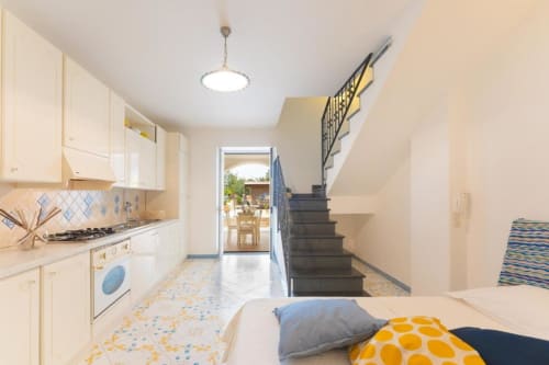 Luminosa cucina-soggiorno con scala presso IL POETA, Procida, con mobili color crema e dettagli blu