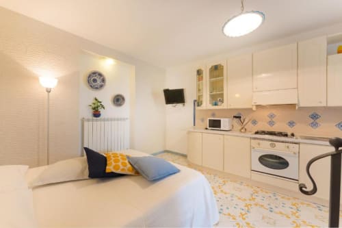 Luminoso monolocale a IL POETA a Procida con letto, cucina, microonde e zona pranzo arredati in bianco e crema
