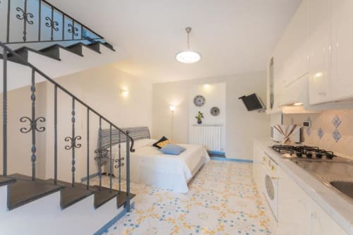 Camera della locanda Il Poeta a Procida con letto a soppalco, angolo cottura e pavimento in maiolica blu tradizionale