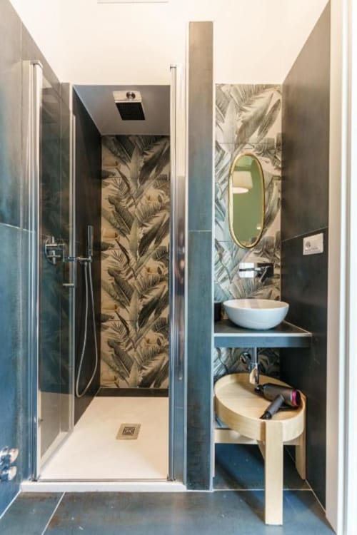 Bagno moderno a IL POETA Procida con carta da parati tropicale, lavabo d'appoggio, specchio rotondo e doccia con soffione pioggia