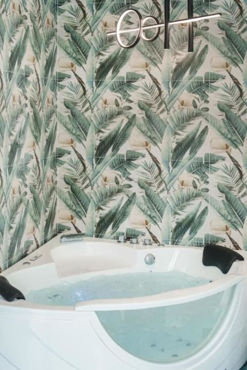 Vasca idromassaggio moderna con acqua azzurra a IL POETA, Procida. Carta da parati foglie tropicali, rubinetteria cromata e nero