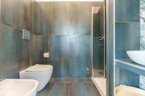 Bagno moderno presso IL POETA a Procida con piastrelle blu-turchesi, doccia walk-in e sanitari bianchi