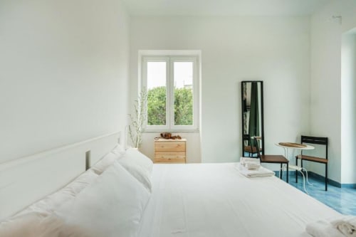 Luminosa camera da letto principale a IL POETA, Procida con biancheria bianca, cassettone in legno e finestre con vista sul mare