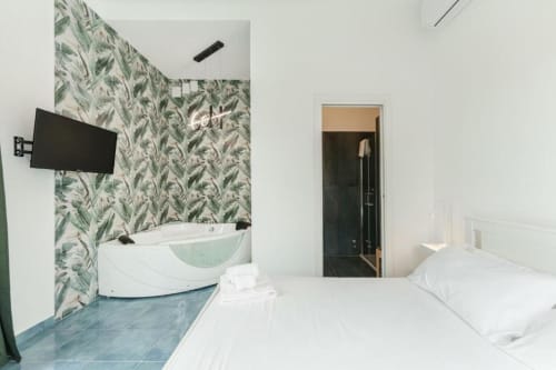 Camera da letto moderna con vasca integrata, carta da parati botanica e vista sul mare presso IL POETA a Procida