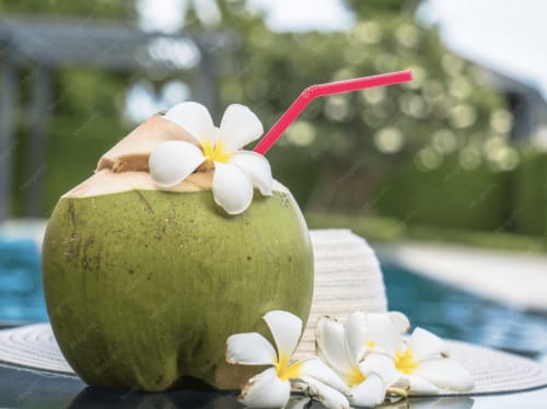 Cocktail tropical à la noix de coco avec fleurs blanches à la piscine du resort Fare Tihi Moana, Raiatea