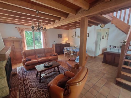 Spacieux séjour de cottage avec poutres apparentes, mobilier en cuir et vue sur le jardin à Locmaria Belle Île en Mer