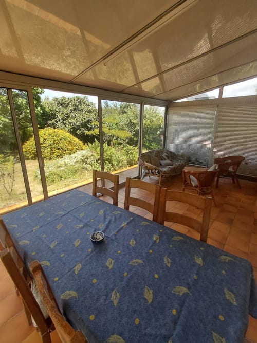Salle à manger ensoleillée à la véranda de la maison Lannivrec, Belle Île en Mer, avec vue sur le jardin et sièges confortables