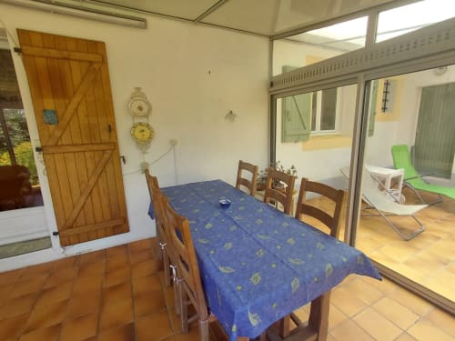 Coin repas du gîte Maison Lannivrec à Locmaria avec table en bois, chaises et vue sur le jardin par les portes vitrées