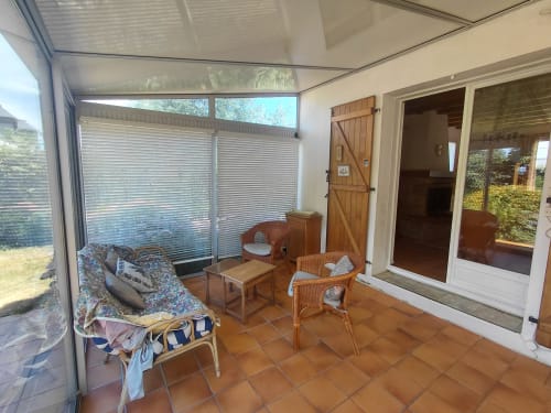 Terrasse ensoleillée avec mobilier en rotin, salle à manger et porte en bois à la maison Lannivrec, Belle-Île-en-Mer