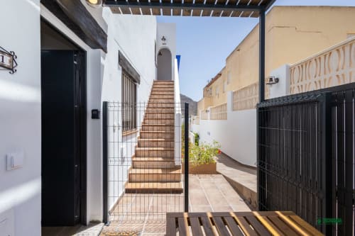 Manbea Almería courtyard with terracotta stairs, white-walled buildings, and black metal gates under clear sky