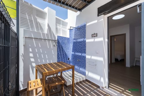 Sunny outdoor shower area at Manbea 11, Almería with wooden furniture and blue mosaic tiles