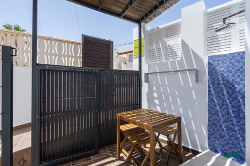 Manbea 11 room terrace in Almería with wooden table, black gate, and blue tile wall