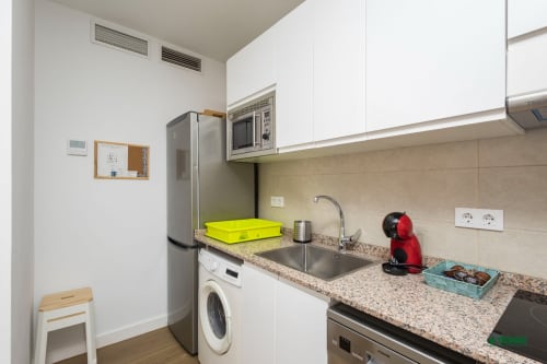 Modern kitchen in Manbea 11 apartment, Almería with stainless steel appliances, granite countertop, and white cabinets