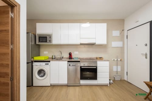 Modern kitchen in Manbea 11 apartment, Almería with white cabinets, stainless steel appliances and wooden flooring
