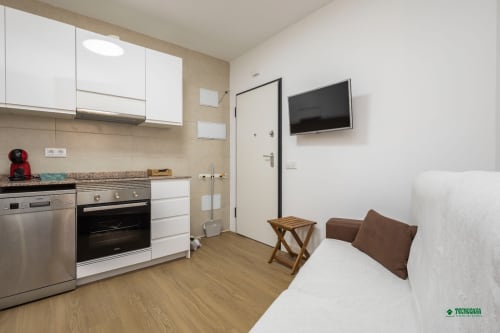 Modern studio apartment at Manbea Almería with kitchenette, bed, sofa, and wall-mounted TV