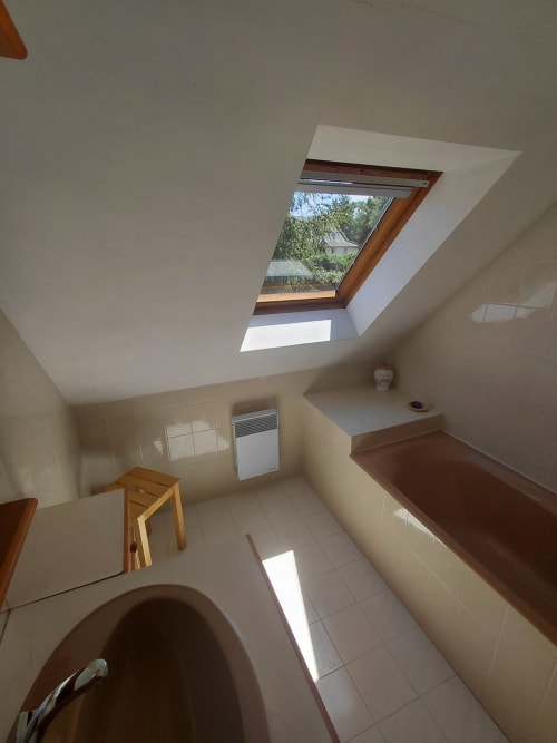Salle de bains lumineuse avec puits de lumière dans le gîte Locmaria, baignoire et finitions en bois