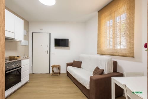 Manbea 11 studio in Almería with brown sofa, kitchenette, TV, and natural light from window