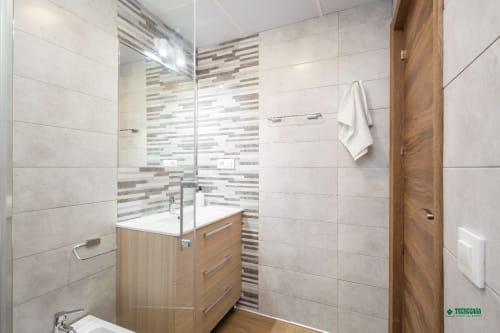 Modern bathroom at Apartamentos Manbea in Almería with walk-in shower, wooden vanity, and tile accents
