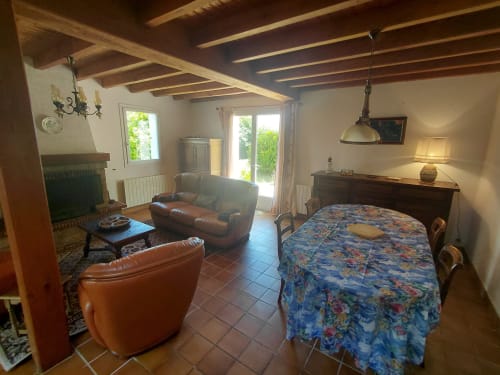 Spacieuse chambre de cottage avec sièges en cuir, cheminée et portes donnant sur le jardin à Locmaria, Belle Île en Mer