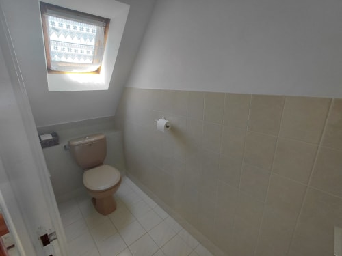 Salle de bain épurée avec toilettes, carrelage beige et fenêtre de toit à la Maison Lannivrec, Locmaria Belle Île en Mer