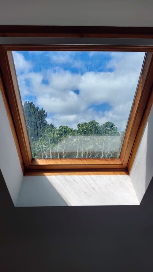 Vue par la verrière de la forêt verte et du ciel bleu depuis la chambre d'une chaumière à Belle-Île-en-Mer, Bretagne