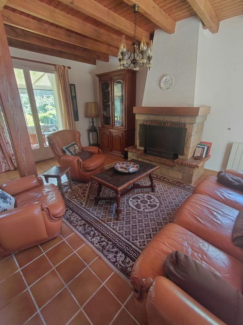 Salon spacieux avec sièges en cuir, cheminée et poutres apparentes à la Maison Lannivrec, Belle-île-en-Mer