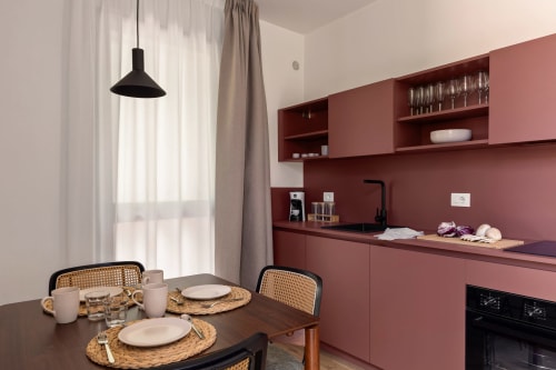 Zona cucina-soggiorno moderna presso Dimora Silva Nature Suites con mobili in terracotta, tavolo in legno e luce naturale