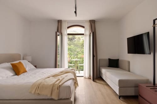 Camera luminosa a Dimora Silva Nature Suites con porte-finestre ad arco, letti gemelli, pavimenti in legno e vista sulla natura