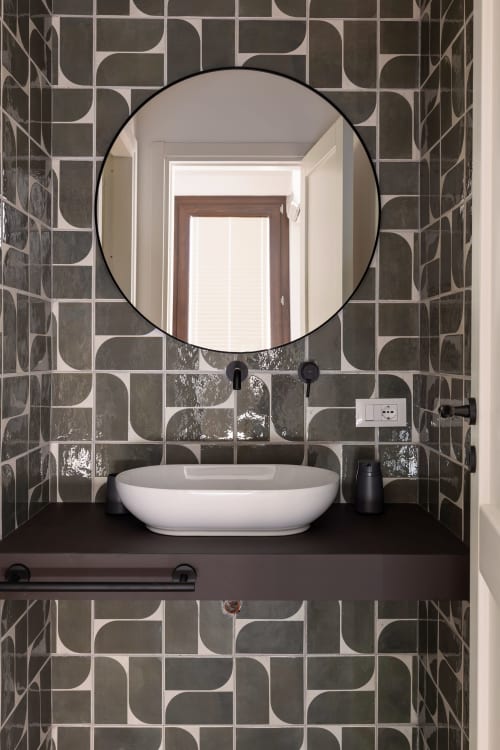 Bagno moderno presso Dimora Silva Nature Suites con specchio rotondo nero, lavabo bianco a bacinella e pareti geometriche