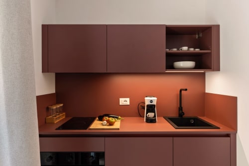 Angolo cucina moderno presso Dimora Silva Nature Suites con schienale in cotto, mobili color bordeaux, piano cottura, lavello e caffè