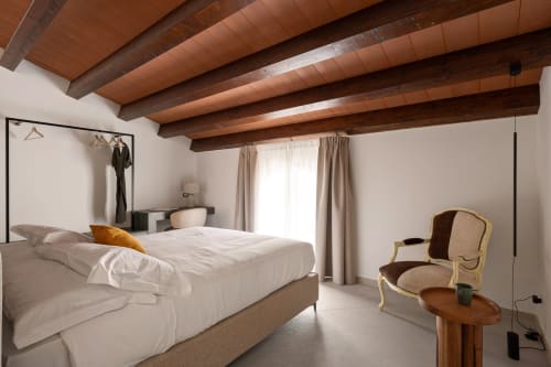 Spacious bedroom at Dimora Silva Nature Suites with exposed wooden beams, white linens, and elegant furnishings in San